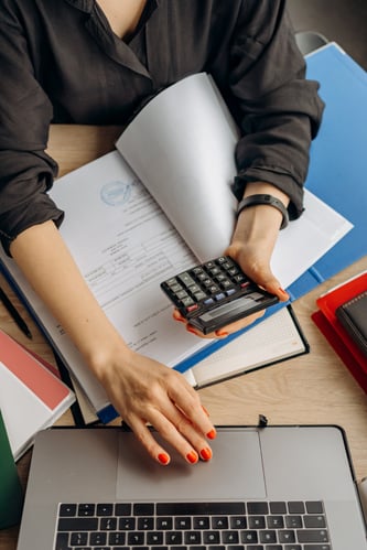 Person working on laptop while calculating something